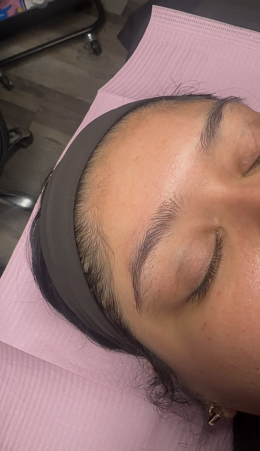 Before: the client's full, untamed natural brows, with a headband holding back her hair.
